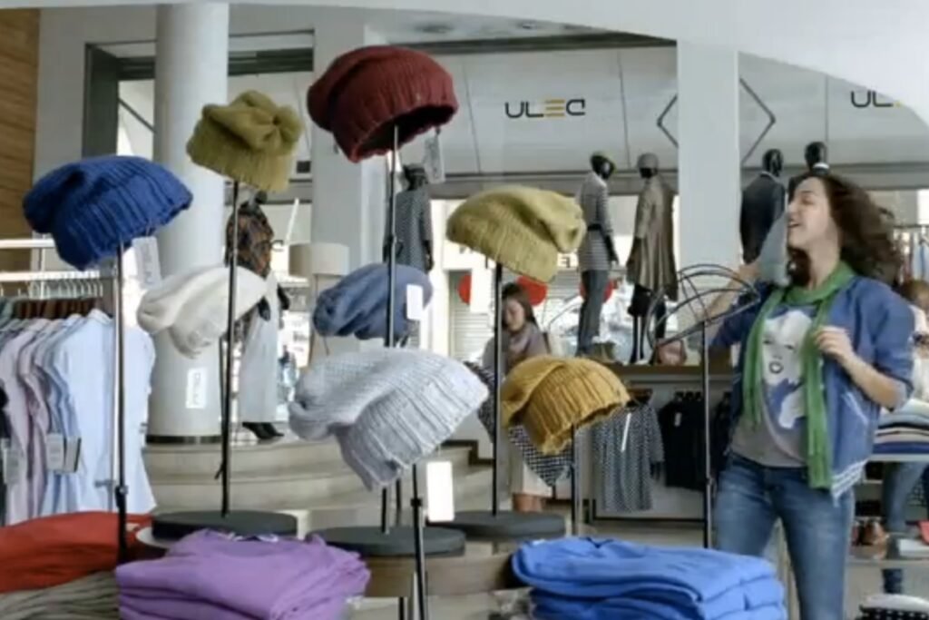 Still shot of AT&T commercial featuring numerous knitted beanies on stands inside a clothing store
