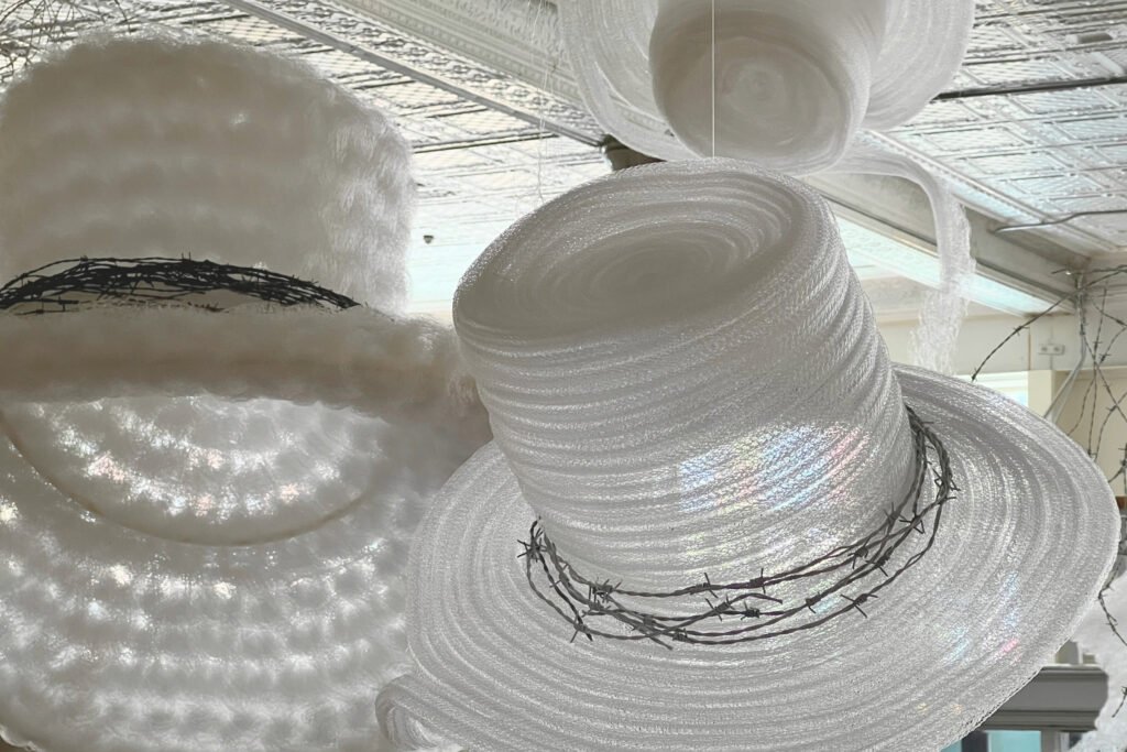 Stampede, closeup view of a large scale installation of hanging cowboy hats and tumbleweeds