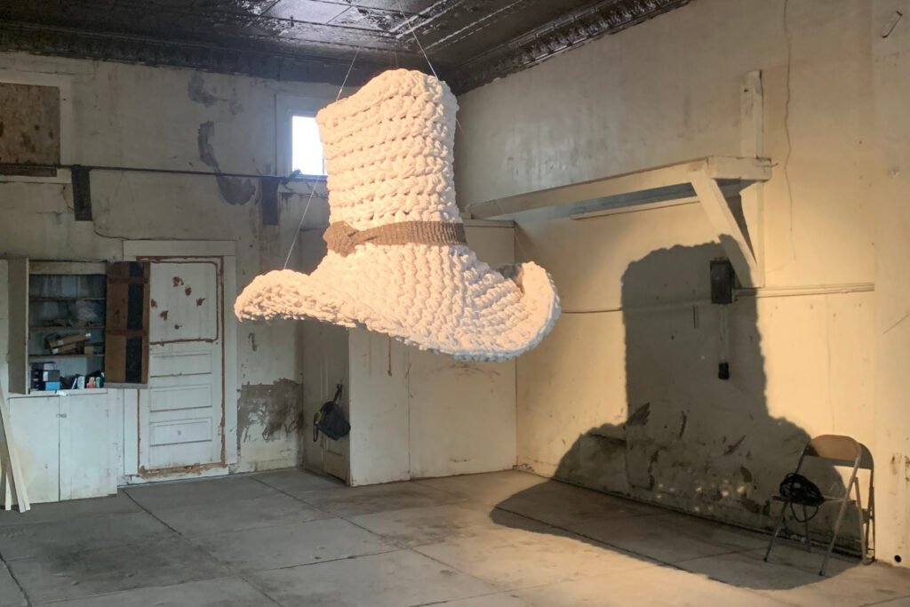 Tom Mix Wept large scale fiber sculpture of a crocheted cowboy hat hanging in a garage turned gallery